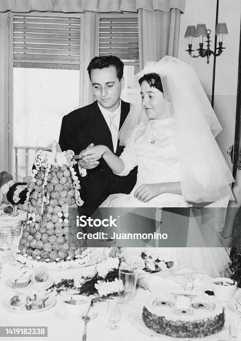 istock Vintage image from the 50s : Young couple posing cutting their wedding cake 1419182338