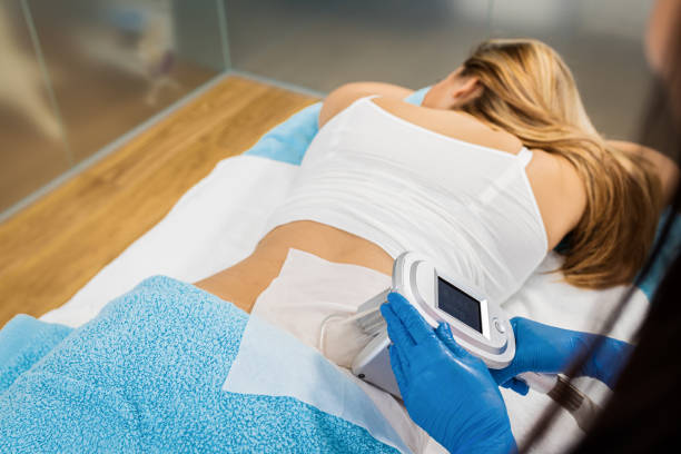 Beautician therapist applying cryolipolysis treatment in beauty salon. stock photo