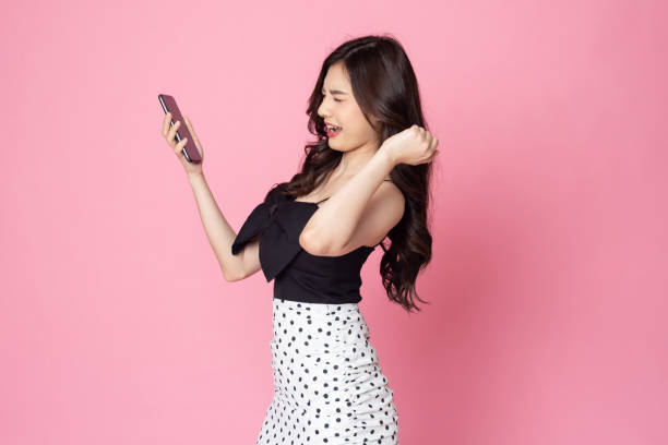 istock portrait asian young Women are happy while using smartphone isolated on pink background 1419208825