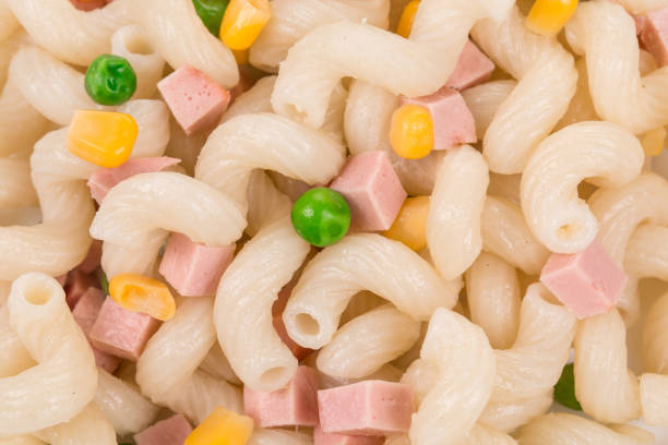 Pasta cavatappi with vegetables and sausage on a white plate. It is occupies the entire surface of the image. Close-up.