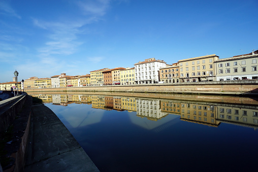 View of old buildings stretching along the Arno Riveพ. Beautifully reflected in the water, Pisa, Italy