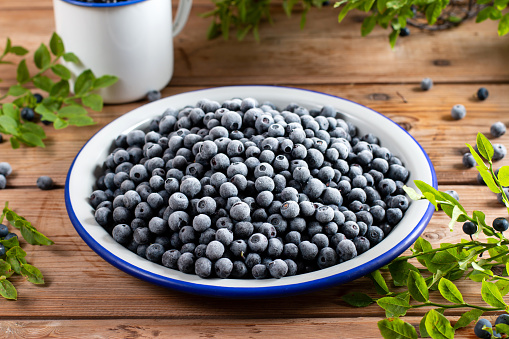 Metal bowl with frozen blueberries on rustic wooden table. Frozen berries.