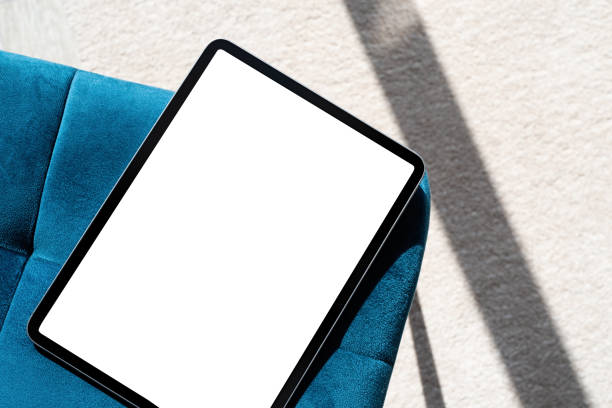 Digital tablet computer with isolated screen on blue chair. At home interior.