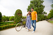 Couple embraced while walking together with a bike in a park