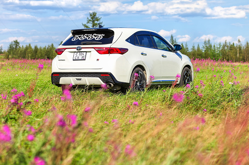 Novyy Urengoy, Russia - July 21, 2022: White luxury crossover Toyota Harrier in a field of willowherb.