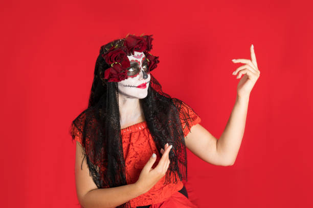 Portrait of a young woman in a red dress and traditional sugar skull makeup for the celebration of Dia de los Muertos, the Day of the Dead stock photo