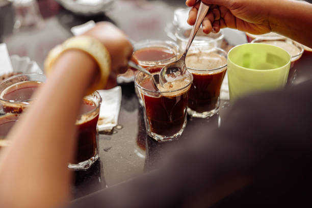 Cropped photo of cup taster man with spoons in hands tasting degustation coffee. Quality test