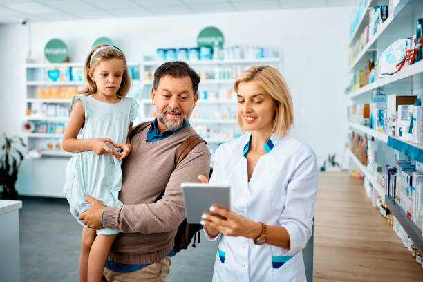 istock Happy pharmacist using touchpad while assisting little girl and her father in a pharmacy. 1419245940