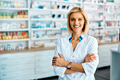 Portrait of confident female pharmacist in drugstore looking at camera.
