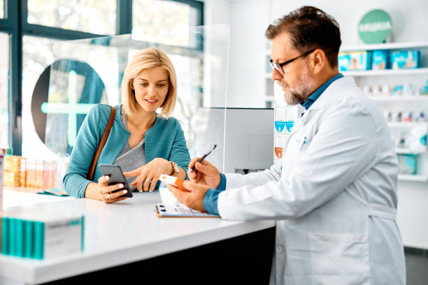 mid adult woman buying prescription medicine in drugstore. - kas bouwwerk stockfoto's en -beelden