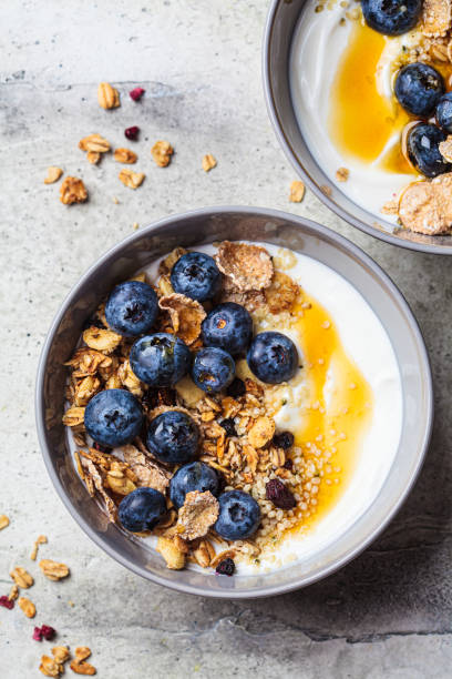 Breakfast coconut yogurt bowl with granola, blueberries and maple syrup, gray background. stock photo