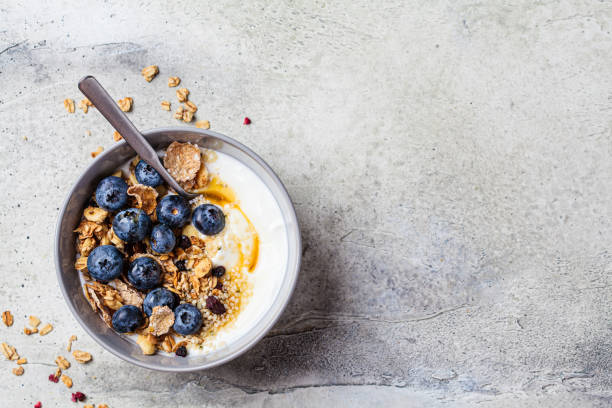istock Breakfast yogurt bowl with granola, blueberries and maple syrup, gray background. 1419246827