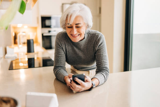 istock Elderly woman speaking to a smart device in her home 1419246831