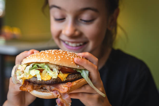 istock A little girl eats an appetizing burger, close-up. 1419247053