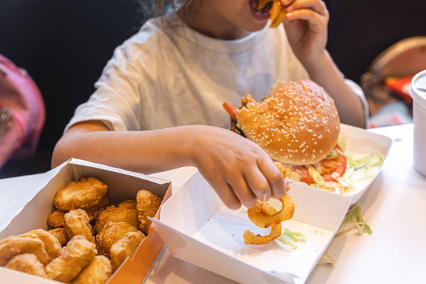A little girl eats fast food in a cafe. stock photo