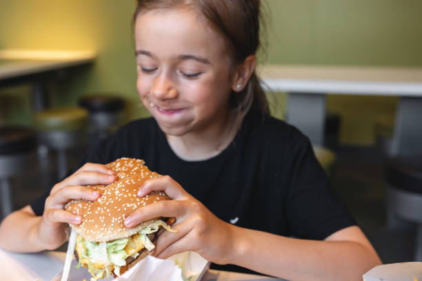 istock A little girl eats an appetizing burger, close-up. 1419247071