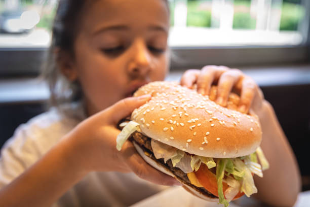 istock A little girl eats an appetizing burger, close-up. 1419247076