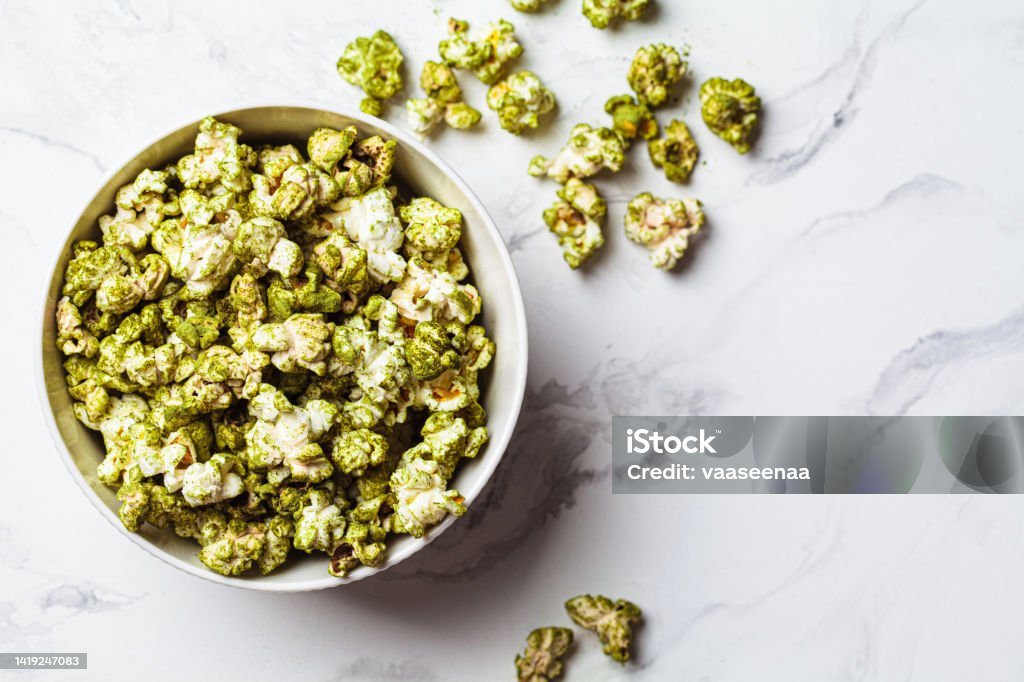 Green spirulina popcorn in white bowl. Alternative food, healthy dessert, plant-based diet. Vegan green spirulina popcorn in a white bowl, top view. Alternative food, healthy dessert, plant-based diet. Above Stock Photo