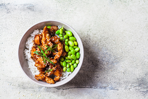 Teriyaki chicken with rice , onion and edamame beans in a gray bowl, top view. Japanese cuisine.