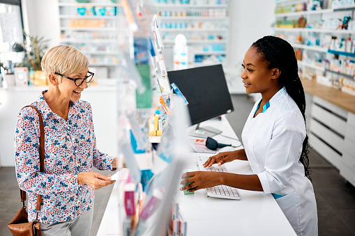 Happy senior woman buying prescription medicine in a pharmacy.