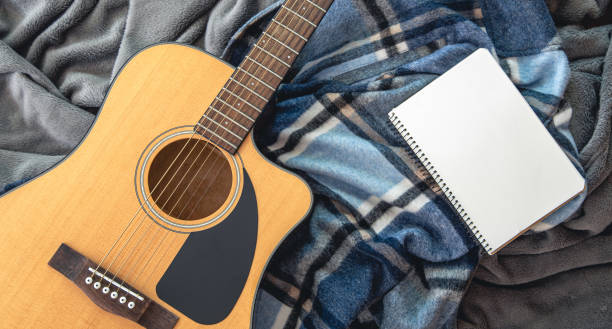 istock Acoustic guitar and notepad on a plaid background, top view. 1419248584