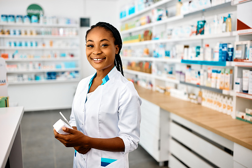 Young African American female pharmacist at work looking at camera.