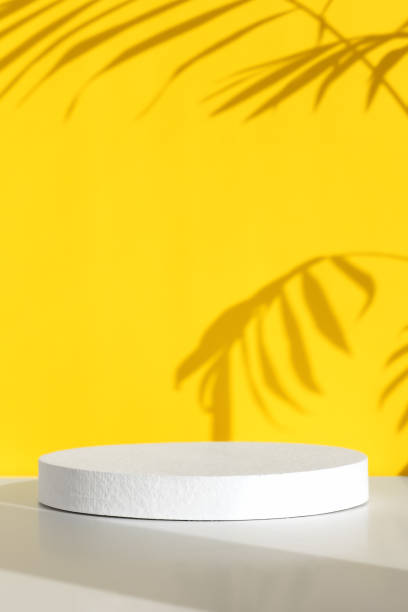 istock Minimal abstract yellow and white background for eco cosmetic product presentation. Cylindrical white scene. Premium podium with a shadow of tropical palm leaves. Empty showcase. 1419256855