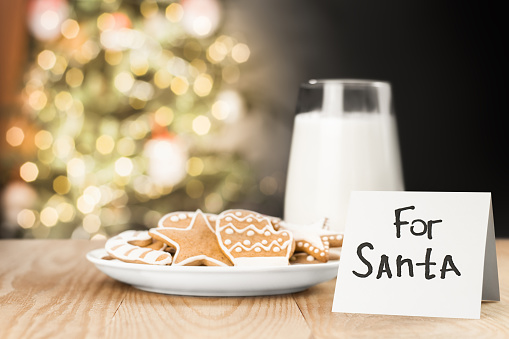cookies, milk and a note for Santa on the table against the background of the Christmas tree