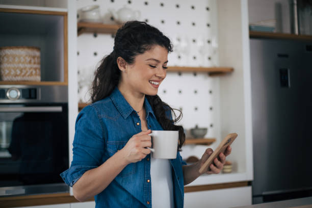 istock Beautiful woman in kitchen using phone 1419258899