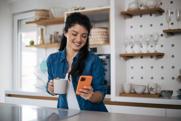 istock Beautiful woman in kitchen using phone 1419259051