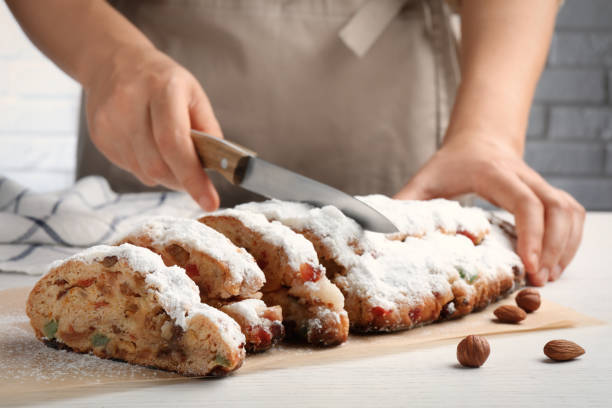 mujer cortando stollen navideño tradicional con azúcar glas en mesa de madera blanca, primer plano - marzipan fruit celebration dessert fotografías e imágenes de stock