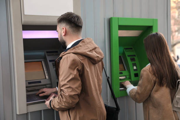 istock Young man using cash machine for money withdrawal outdoors 1419266074