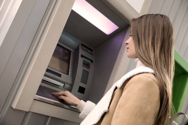 istock Young woman entering cash machine pin code outdoors 1419266983
