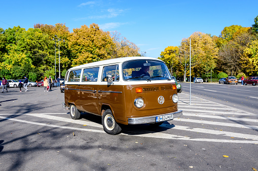 Bucharest, Romania, 24 October 2021: Vivid brown Volkswagen combi vintage van (also called transporter or bus) in traffic in a street at an event for vintage cars collections, in a sunny autumn day