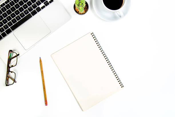 istock top view of white desk with blank notebook, computer keyboard and other office equipment Top view with copy space, laid flat. 1419271394
