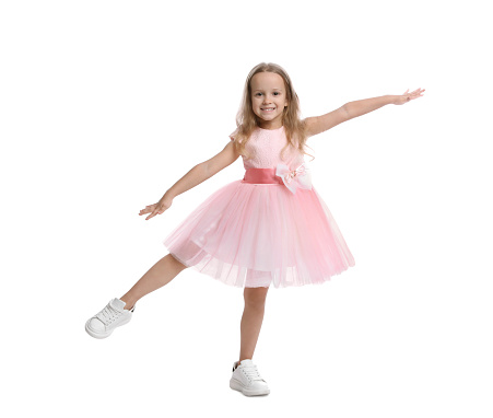 Cute little girl in beautiful dress dancing on white background