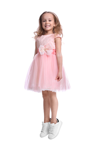 White-skinned Latina girl with short hair is inside a photo studio where she models a line of children's clothing while enjoying the moment and looking at the camera.