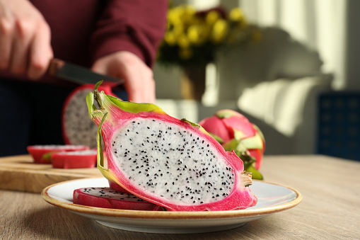 Plate with delicious cut white pitahaya fruit on wooden table indoors, closeup