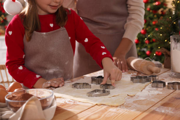madre y su hija haciendo deliciosas galletas navideñas en una mesa de madera en el interior, primer plano - cortador de masa fotografías e imágenes de stock