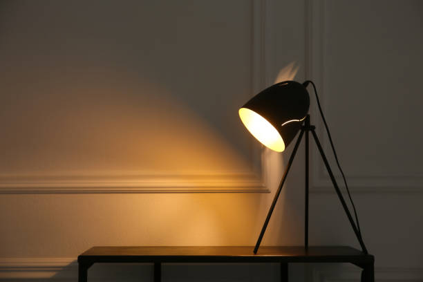 istock Wooden table with modern lamp near beige wall, space for text. Interior element 1419277185