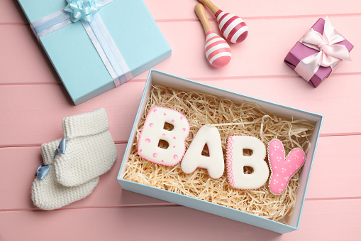 Baby shower party. Flat lay composition with gift boxes and cookies on pink wooden background
