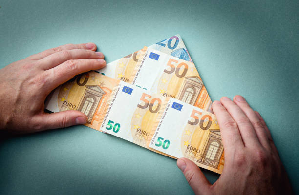 Pyramid scheme or Ponzi scheme concept. Euro money folded as pyramid shape and man showing on blue background, studio shot. Pyramid scheme or Ponzi scheme concept. Euro money folded as pyramid shape and man showing on blue background, studio shot. ponzi scheme stock pictures, royalty-free photos & images