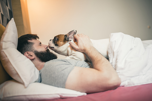 Men cuddling with his dog in the morning in the bedroom