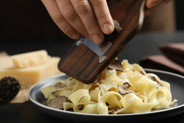 istock Woman slicing truffle onto tagliatelle at table, closeup 1419281160