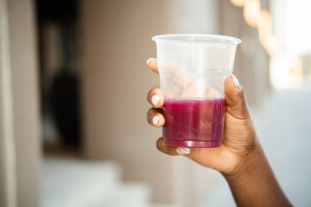Close-up shot of a women's hand holding a disposable plastic cup of juice