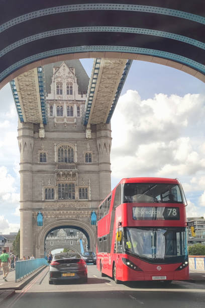 Cars and a red London bus driving across Tower Bridge in London Tower Bridge Road, London, England, UK - Cars and a New Routemaster double-decker bus or Boris bus driving across the River Thames beneath the towers of Tower Bridge. Pedestrians can also be seen walking across the bridge. The historic suspension bridge was built in the nineteenth century. boris bus stock pictures, royalty-free photos & images