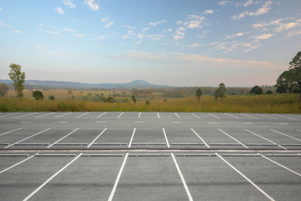 Empty parking lot against meadow and beautiful sunset sky.