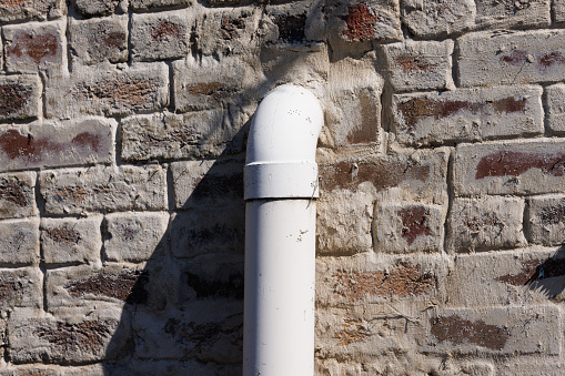 White plastic pipe in an old brick wall.