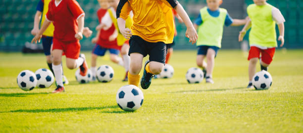 축구 훈련 캠프. 축구 축구 어린이 훈련 수업. 잔디밭에서 축구를 연습하는 아이들. 축구공을 달리고 걷어차는 학교 아이들 그룹 - 드리블 스포츠 뉴스 사진 이미지