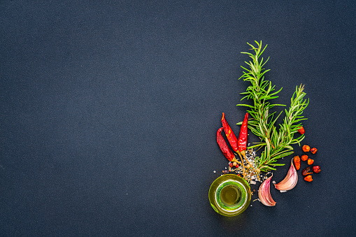 Culinary background: overhead view of herbs and spices arranged at the right of a black background leaving useful copy space for text and/or logo at the left. High resolution 42Mp studio digital capture taken with Sony A7rII and Sony FE 90mm f2.8 macro G OSS lens